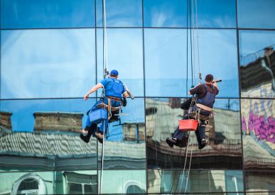 Two rope access technicians cleaning a glass façade